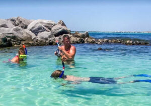 A crew member snorkeling with children at the jetties in Destin